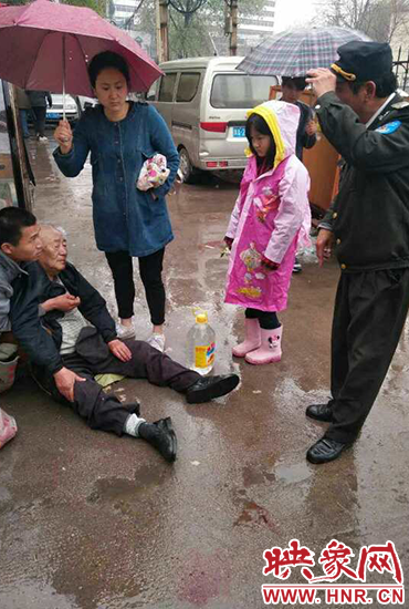 女孩為倒地老人撐傘。