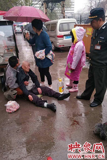 女孩為倒地老人撐傘。