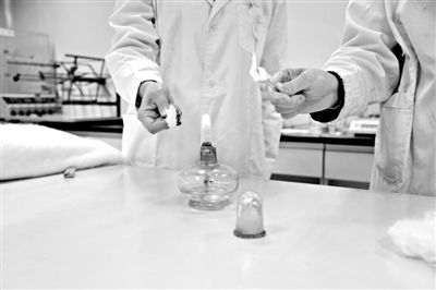 實(shí)驗(yàn)人員操作的燃燒檢測(cè)法中，真蠶絲離開(kāi)火焰就熄滅(左)。