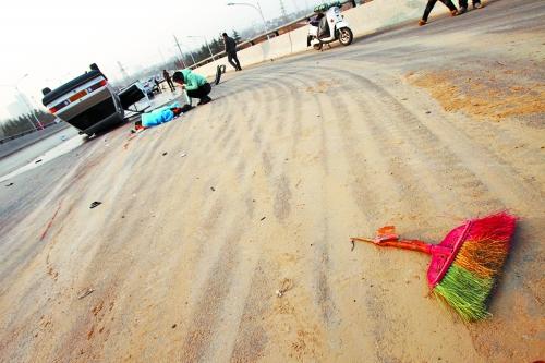 被撞的環(huán)衛(wèi)工躺在地上，身上蓋著藍(lán)色布塊，現(xiàn)場除散落的汽車碎片外，還留有被撞斷的掃帚。