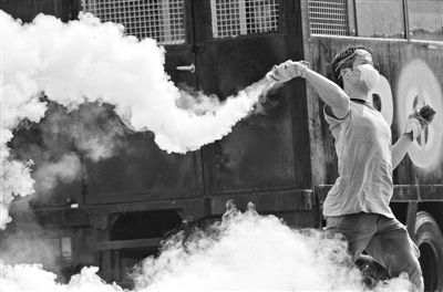 12月2日，泰國曼谷，一名反政府示威者在總理府附近向負(fù)責(zé)執(zhí)勤的警察投擲催淚彈。英拉請(qǐng)求示威者不要再試圖占領(lǐng)政府工作部門，不要逼迫政府工作人員選邊站。