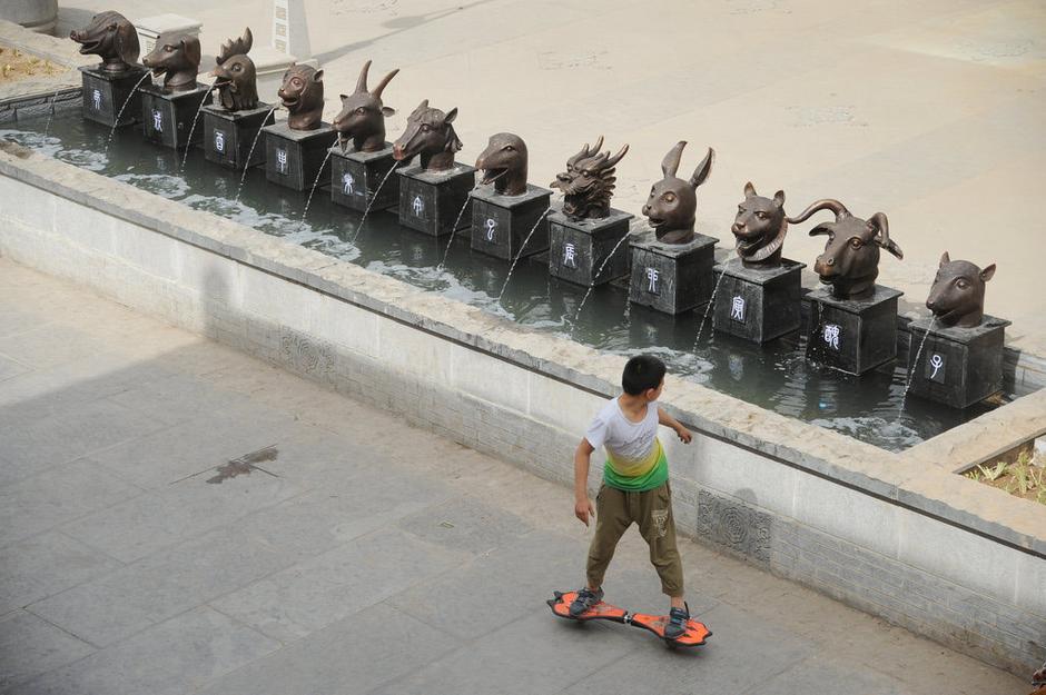 圖為一名市民從獸首旁經(jīng)過。