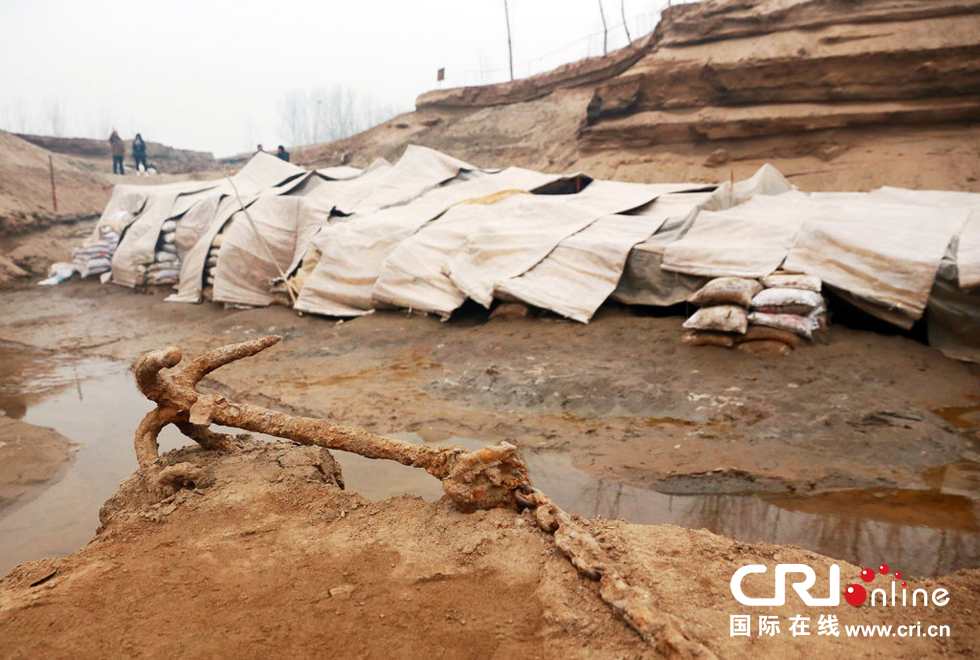 2014年1月6日，河南洛陽古沉船發(fā)掘現(xiàn)場，古沉船鐵錨從見天日，靜靜地躺在古船旁。
