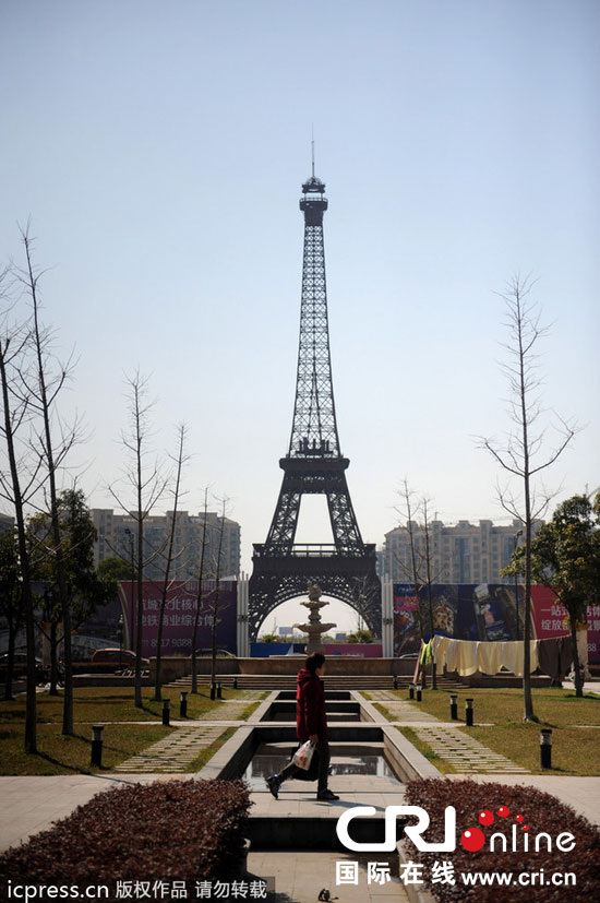 　2014年3月21日，杭州天都城，農(nóng)民在山寨埃菲爾鐵塔下耕作。圖片來源：東方IC