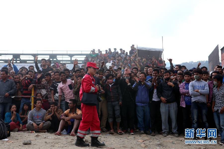 圍觀的尼泊爾民眾在中國國際救援隊成功搜救出幸存者后向搜救隊員歡呼致意。