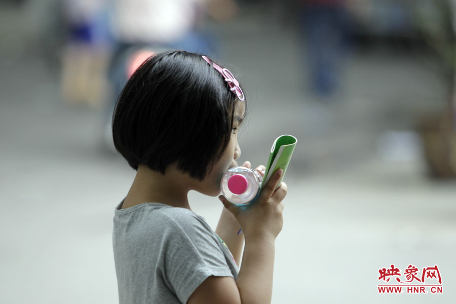 6月7日，鄭州回中考點，一名孩子拿著一瓶礦泉水，等待哥哥走出考場