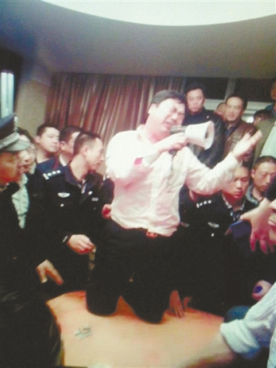 　4月19日，泰州市濱江工業(yè)園區(qū)管委會招待中心，一男子跪在酒桌上喊話求饒。李根 攝