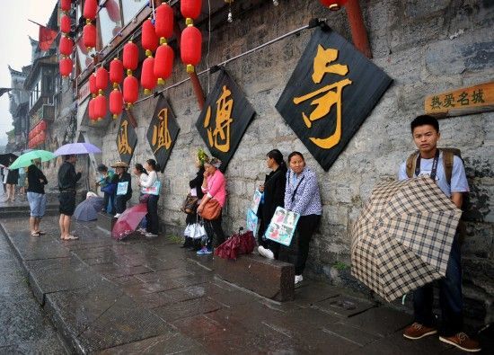 　4月29日上午11時(shí)20分，一些游客和古城當(dāng)?shù)氐木用穸阍谝粋€(gè)酒吧的屋檐下避雨。這些當(dāng)?shù)鼐用褚詾橛慰团恼罩\生，一場(chǎng)降雨讓他們的生意更加清淡。