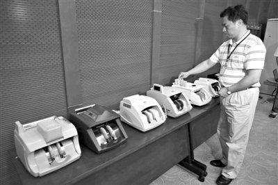 昨日，央行工作人員用各種驗鈔機對C1F9假幣進(jìn)行測試，機器均能及時作出異常報警反應(yīng)。新京報記者 浦