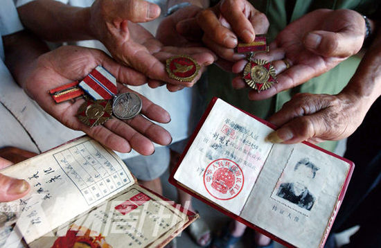 幾位志愿軍老兵展示自己的立功證、傷殘軍人證與勛章