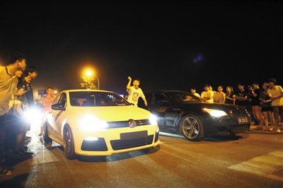 8月24日晚，東壩中街飆車現(xiàn)場，兩輛車并排等待出發(fā)指令，旁邊許多愛好者前來觀看比賽。新京報記者