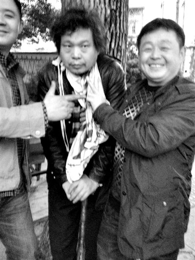 兩名接訪人員與患有癌癥的訪民段新德合影時，面帶笑容擺出勝利的手勢。