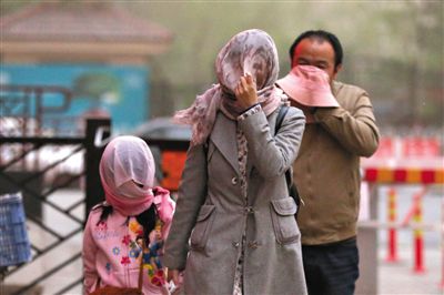 昨日下午，朝陽區(qū)豆各莊，行人將紗巾裹在頭上防沙塵。