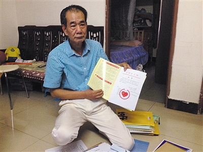 翻出一家網(wǎng)站贈予的“中國好人”證書，區(qū)少坤單膝跪在地上，“你看，我是中國好人啊。” 范春旭 攝