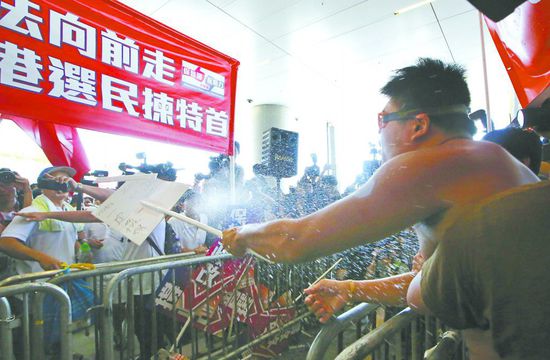 17日，在香港立法會(huì)外，一名反對(duì)政改的男子向支持派人群投擲標(biāo)牌。