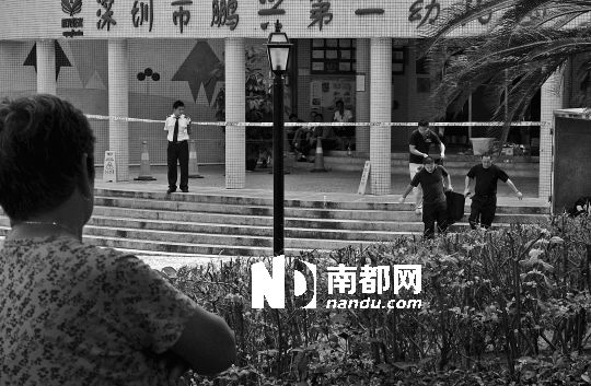 →7月19日，鵬興花園第一幼兒園門前，民警在現(xiàn)場進行完勘查取證后，園長和保安的尸體被運走。南都記者 徐文閣 攝