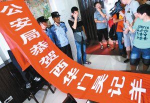 面對警方收繳的條幅，老板楊某也不好意思地用手遮擋臉