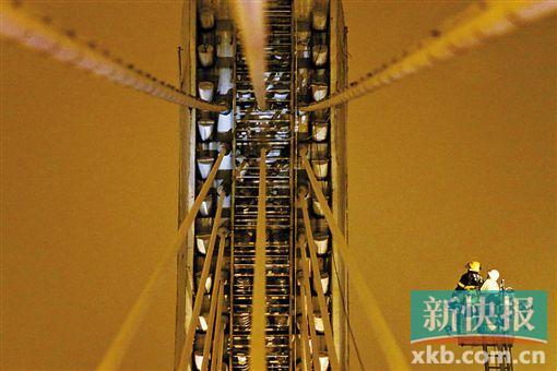 截至今日零時(shí)，男子仍未有下橋舉動(dòng)。圖為公安和消防人員乘消防云梯在高空上和男子交談。
