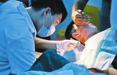 孩子身上有7道傷痕，其中兩道需要縫合，其他的均為擦傷，醫(yī)生正對他施治。