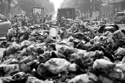 垃圾堆滿整個(gè)路口，環(huán)衛(wèi)工人們正在清理