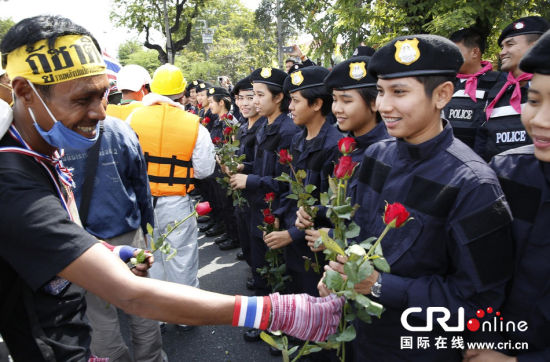 2013年12月03日,曼谷總理府與曼谷警署允許反政府示威民眾進(jìn)入,雙方進(jìn)入暫時“停戰(zhàn)”狀態(tài)迎接泰王生日。曼谷警察總署,女警們手持鮮花送給反政府示威民眾。圖片來源:Manish Swarup/東方IC