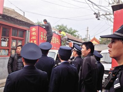 昨日下午,東城區(qū)工商、城管、公安等部門,對(duì)雍和宮附近的預(yù)測(cè)中心進(jìn)行清理整頓,站在車頂?shù)膬擅と苏鸪患摇邦A(yù)測(cè)中心”的招牌。因雍和宮、白云觀等文化景點(diǎn)外聚集大量算命先生,被媒體稱為“算命一條街”。本版攝影/新京報(bào)記者 李寧 攝