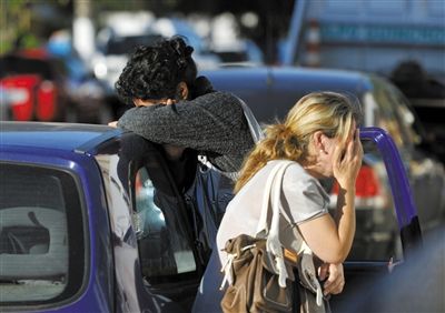 27日，遇難者親友在火災(zāi)現(xiàn)場旁哭泣。