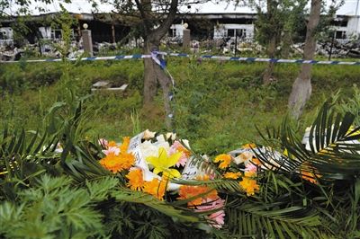 昨日，吉林省德惠市吉林寶源豐禽業(yè)有限公司燃燒事故現(xiàn)場警戒線外，遇難者家屬在路邊擺放了花圈祭奠逝去的親人。吳江 攝