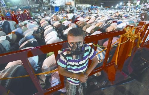 當(dāng)?shù)貢r(shí)間28日晚，在埃及開(kāi)羅納賽爾城，一名小男孩頭戴防毒面具參加穆兄會(huì)的集會(huì)示威。