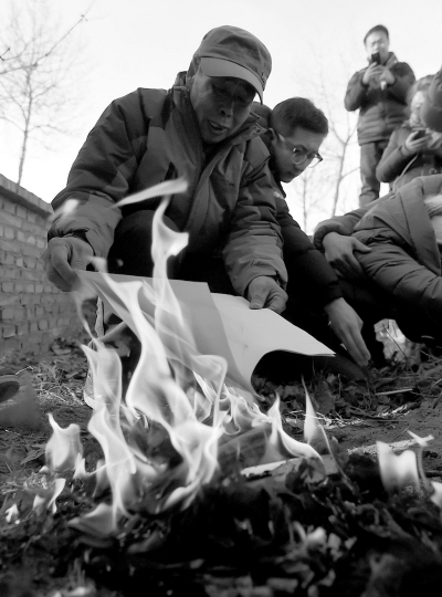 李三仁在兒子墳前焚燒再審無罪判決文書的復(fù)印件。新華社發(fā)