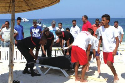 6月26日，在突尼斯蘇塞，救生員和醫(yī)務(wù)人員在發(fā)生襲擊事件的海灘運(yùn)送一名死者的遺體。新華社發(fā)