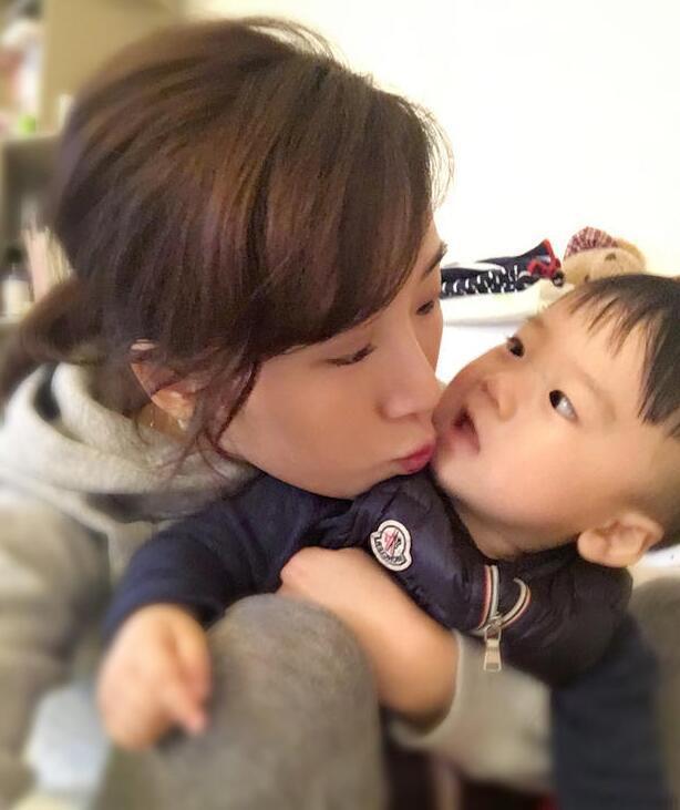 照片中李念狂吻兒子，小寶貝自顧自地玩著。