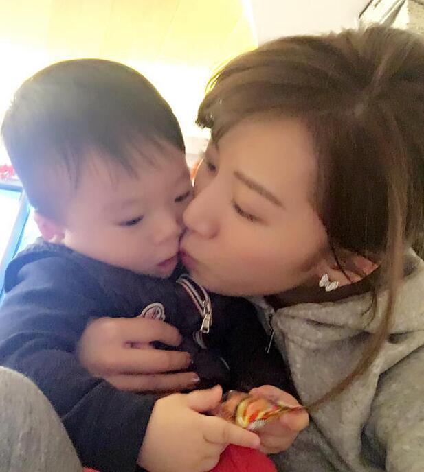 照片中李念狂吻兒子，小寶貝自顧自地玩著。