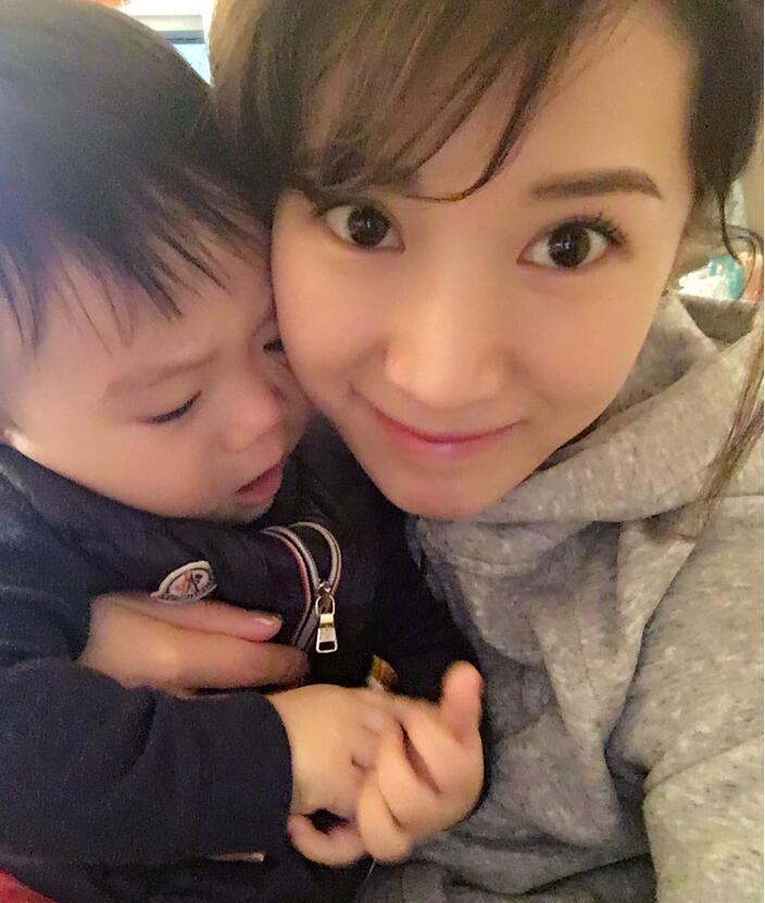 照片中李念狂吻兒子，小寶貝自顧自地玩著。