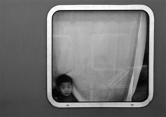 一個(gè)孩子把頭伸向窗外，他想再看送別的親人一眼