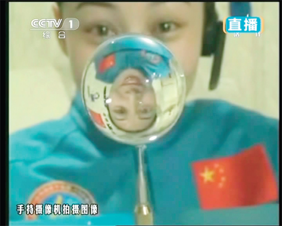 王亞平的倒影出現(xiàn)在水球中。新華社發(fā)（視頻截圖）