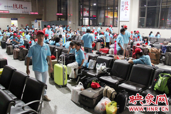 大學(xué)生志愿者在火車(chē)站候車(chē)室內(nèi)整裝待發(fā)。