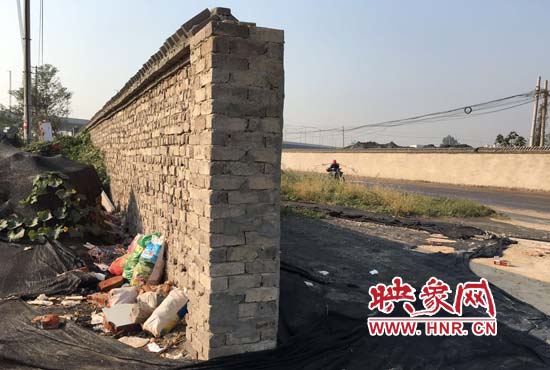 一墻之隔，一邊是道路，一邊是垃圾和荒草，市民質(zhì)疑其為遮羞墻。