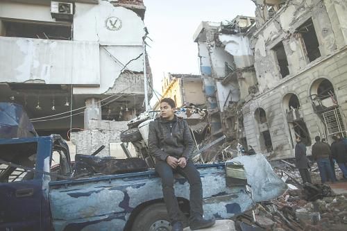 埃及曼蘇拉市警察局24日遭汽車炸彈襲擊，被疑是穆兄會的報復(fù)。圖為一名男子在被炸毀的警察局前。