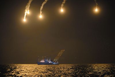 22日，搜救人員在照明彈的光亮下連夜搜救。