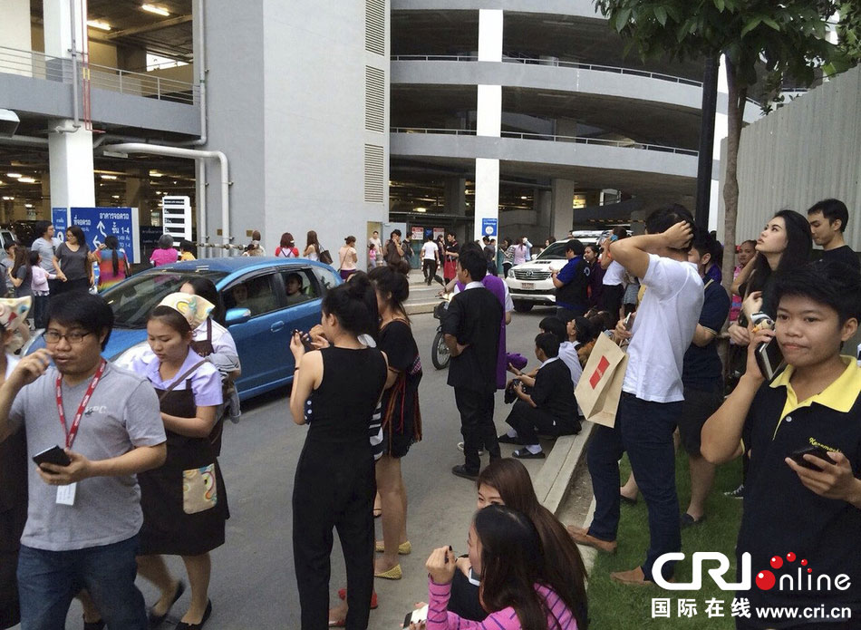 當?shù)貢r間2014年5月5日，泰國清萊，工人們站在一棟大樓外避難。