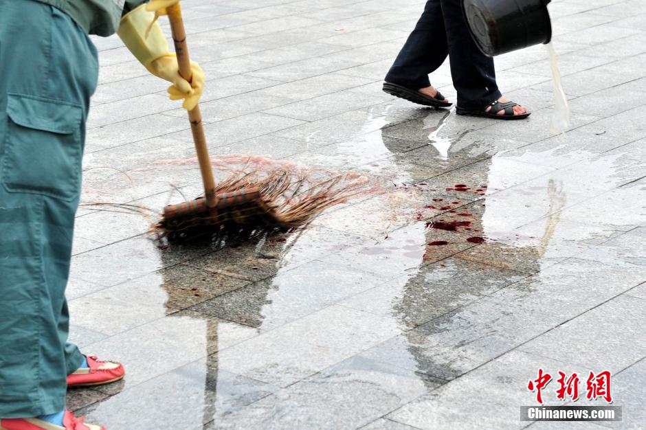 圖為環(huán)衛(wèi)工人在清理案發(fā)地點的血跡。