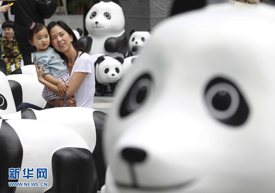 6月2日，一位家長帶著孩子在上海街頭和大熊貓模型合影。