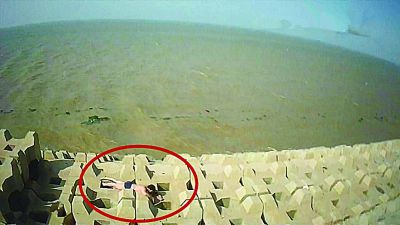 孫正龍游上岸，趴在海邊精疲力盡。