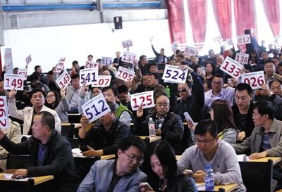 競(jìng)拍者正在練習(xí)舉牌動(dòng)作，以便拍賣時(shí)讓工作人員看清號(hào)牌。