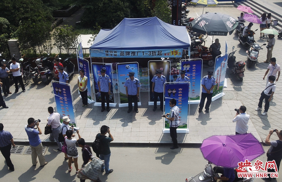 執(zhí)法人員用宣傳牌圍擋占道經(jīng)營(yíng)攤位。