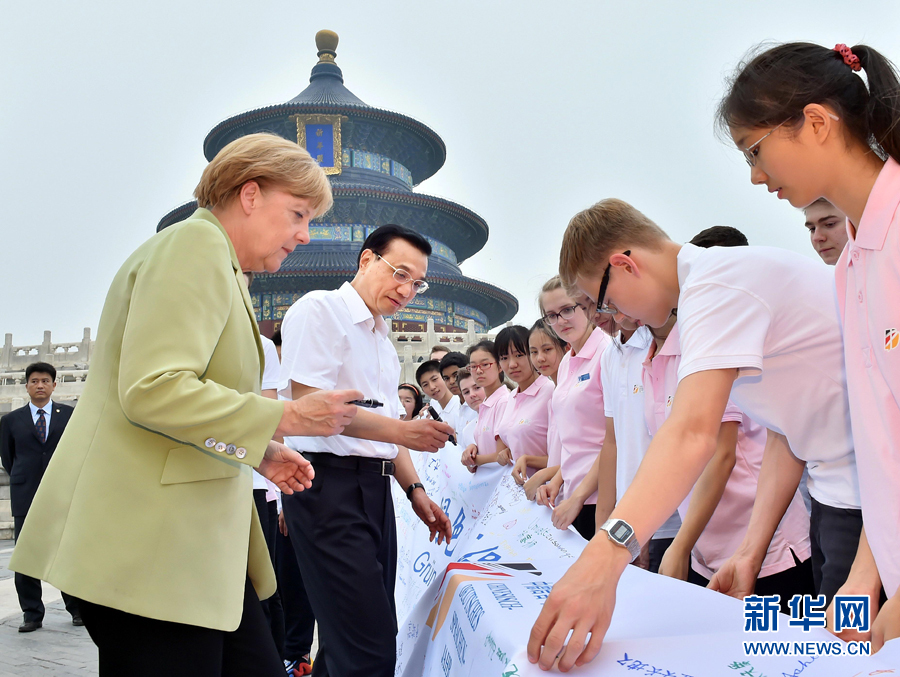 李克強(qiáng)同默克爾在紀(jì)念橫幅上簽名。