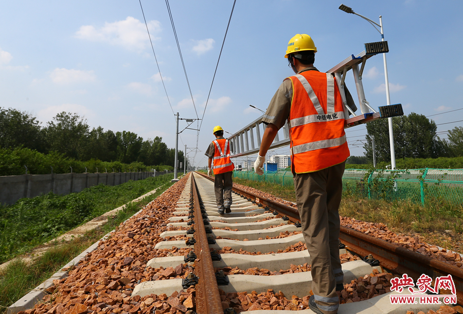 滾燙的鐵軌上，兩個扛著梯子的檢修員走向第四個檢修點