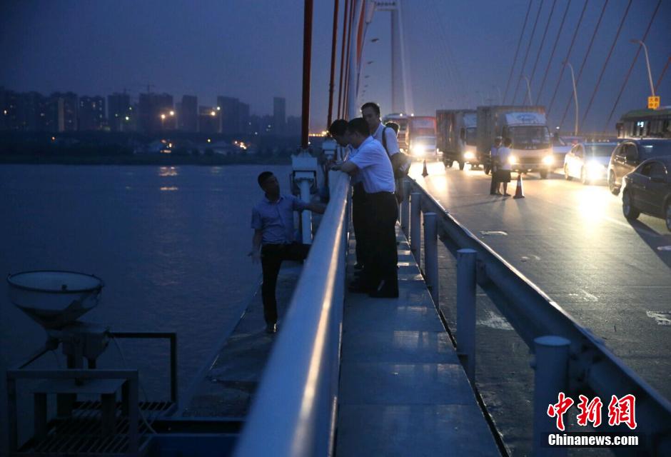 圖為武漢警方談判專家正在與翻爬至大橋外側(cè)護欄的劫持者談判。