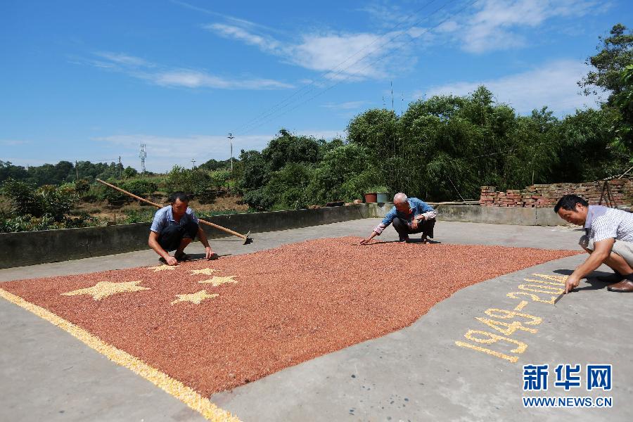 村民馬玉明（左一）用豐收的高粱和玉米在院壩里擺國旗為祖國慶生。